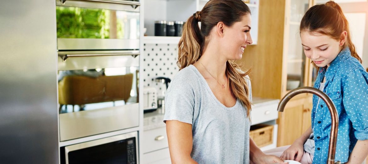 A mum and daughter talking in a kitchen.