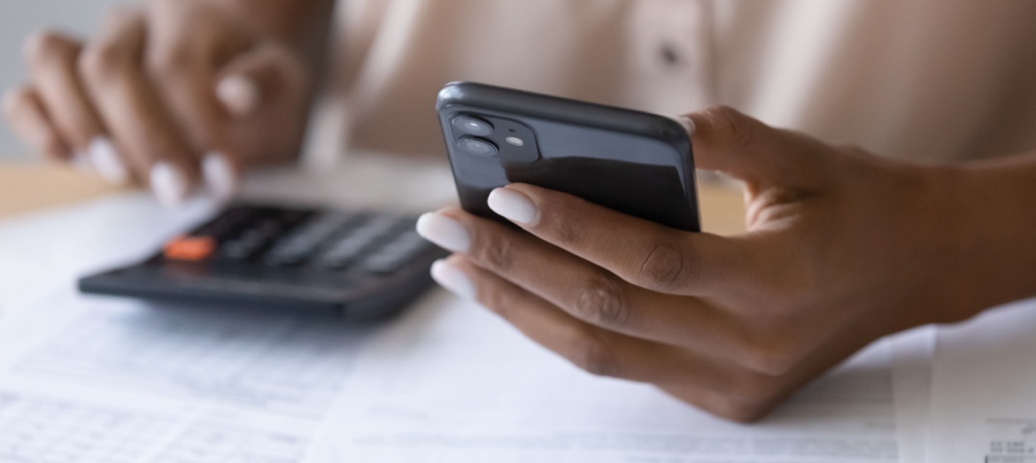 A woman using a calculator while reviewing paperwork.