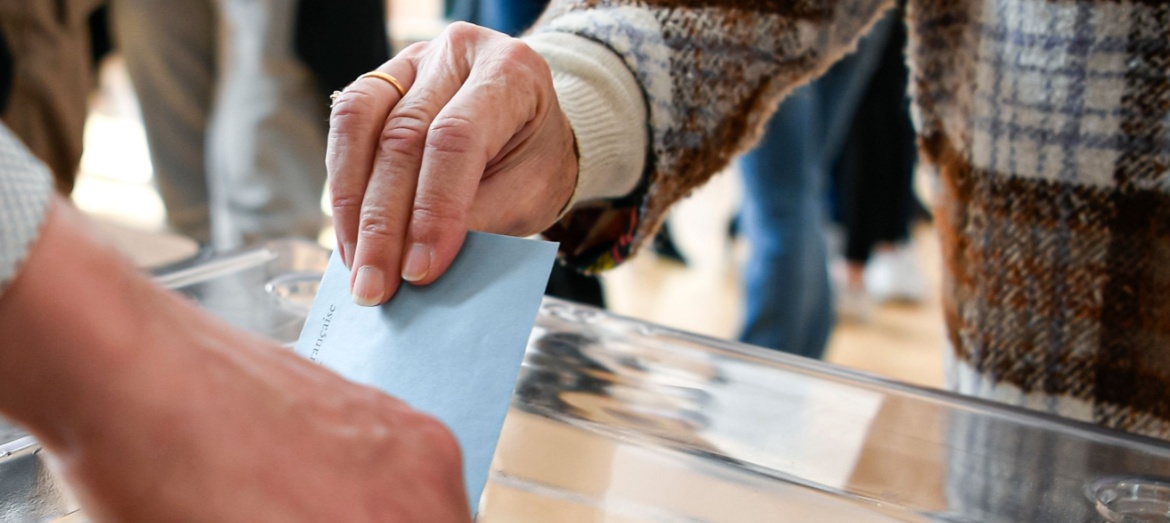 A person putting a ballot paper into a box.