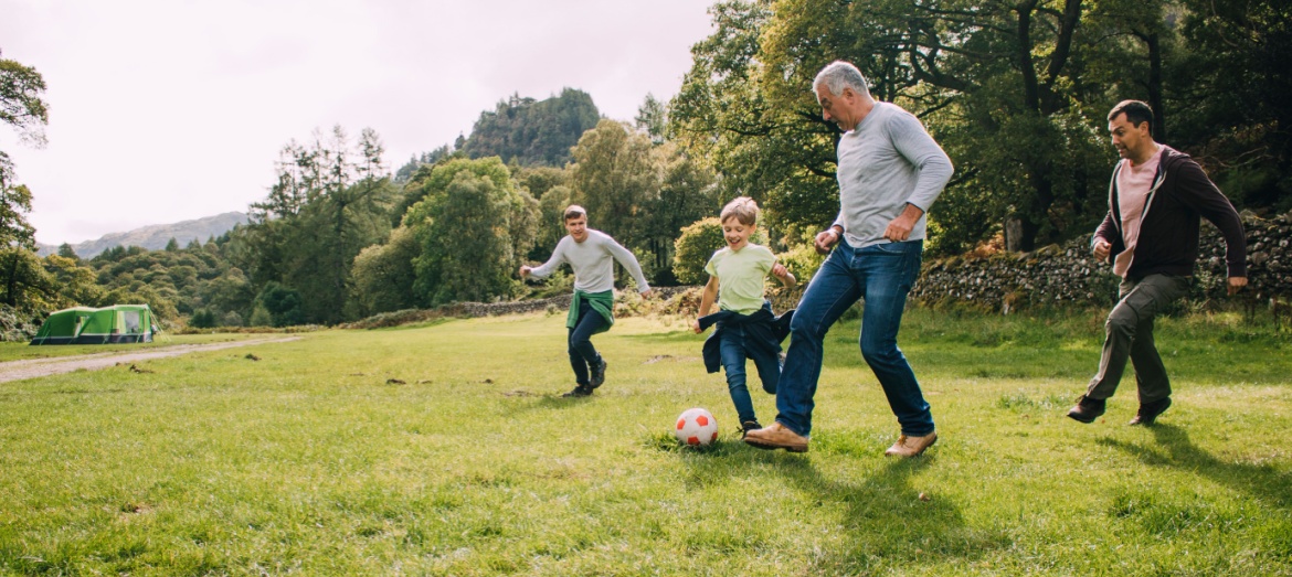 Multi-generational family playing football in a park.