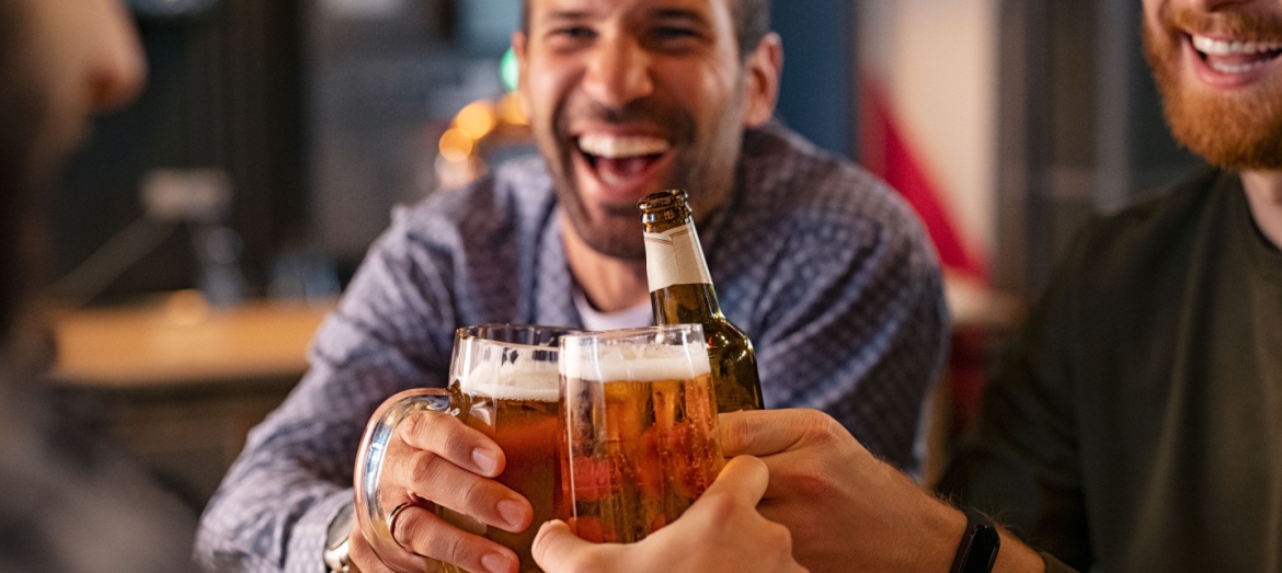 A group of friends clinking beer glasses in a pub.