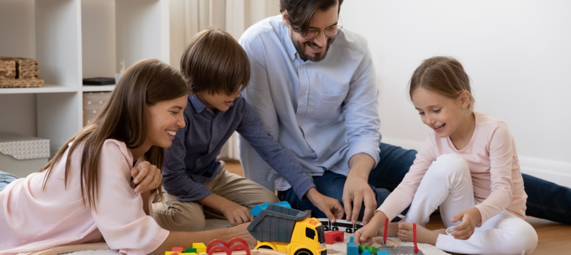 A family with children playing with a train set.