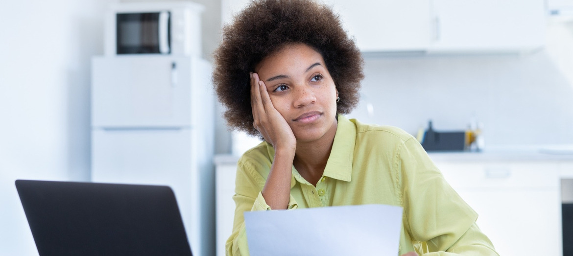 A woman looking stressed while reviewing paperwork.