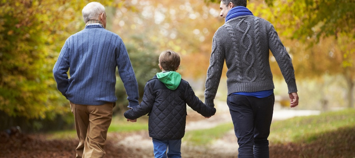 A grandfather walking with his son and grandchild.