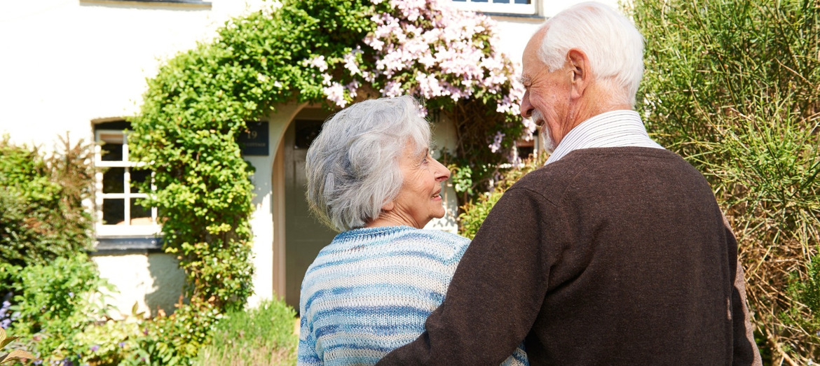 Rear view of senior couple outside pretty cottage